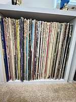 Row of roughly 75 LPs stored vertically in white cube