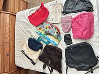 Overview of 11 assorted bags and pouches laid out on bed