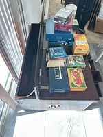 Top view of wooden trunk with lid open and stacked vintage board games