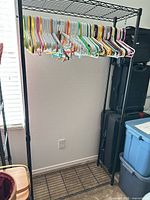 Full view of garment rack with hangers on bar, shows shelves and overall structure