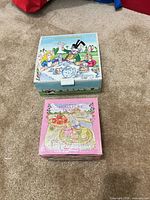 Two illustrated boxes containing miniature tea sets placed on carpet