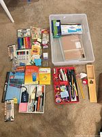 Overview of entire lot laid on carpet showing software boxes, packs of pens, markers, sticky notes, trays, clear bin