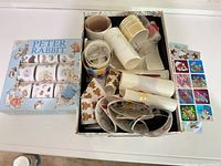 Open gift box showing multiple sticker rolls with visible Peter Rabbit sleeve and assorted holiday designs