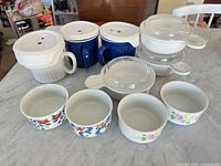 Group view showing handled mugs with lids, glass lids, and all six ramekins