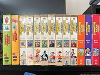 Front spines of eight white VHS volumes and five DVD cases showing titles and artwork