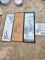 Three vertical prints and mounted print sheet displayed on floor