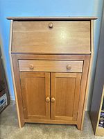 Front view of closed secretary desk showing drawer and cabinet doors