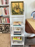 Full view of white ladder shelf with rabbit print on top and books on lower tiers