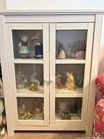 Front view of white two-door cabinet showing glass panels and interior shelves