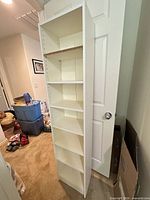 Full front view showing seven shelves and white laminate finish