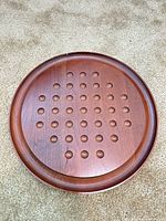 Top view of wooden peg solitaire board showing 33 + 1 holes, wood grain and surface condition