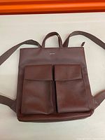 Front view of pebbled brown Matt & Nat backpack with two front pockets