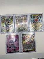 Five sleeved Pokémon cards laid out showing fronts