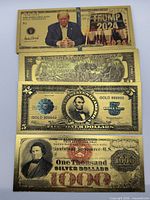 Front view of four assorted gold-foil novelty notes: Trump 2024, CSA $2, US $5, $1000 certificate