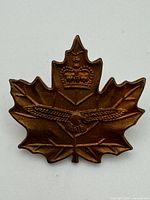 Front view of bronze maple leaf collar pin badge with crown and eagle