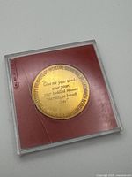 Reverse of medallion showing engraved Emma Lazarus poem excerpt