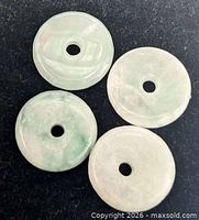 Four jade discs arranged, showing color and drilled holes