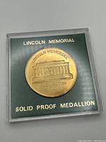 Obverse of medallion showing Lincoln Memorial building and inscriptions within clear case
