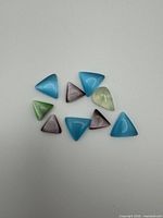Nine assorted triangular cabochon stones laid out on white surface