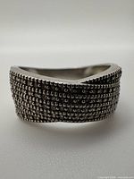 Oblique view of ring showing six-row beaded texture and wave profile
