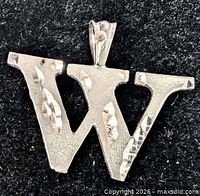 Front view of silver W pendant showing faceted texture and bail