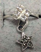 Close view of silver ring with clear stones and dangling star charm