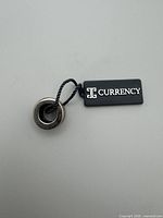 Top view of sterling silver charm bead with attached Currency tag