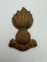 Front view of bronze Royal Artillery collar badge displaying grenade flame and UBIQUE scroll