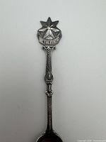 Full view of spoon showing star finial, banner, and handle detail