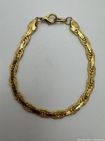 Full view of gold-tone flat chain bracelet showing clasp and woven link design