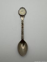 Full view of spoon front showing bowl, decorative stem, enamel crest