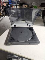 Turntable open with dust cover raised showing platter and tonearm