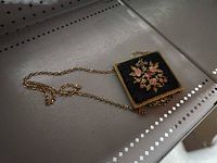 Full view of square purse laying flat showing chain handle and floral embroidery