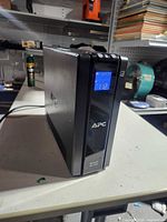 Front left view showing APC Back-UPS Pro 1500 tower with LCD display lit