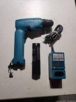 Makita drill, battery, charger grouped on table