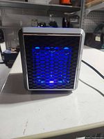 Front view showing illuminated blue grille of heater with power cord