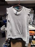 Front view of grey velvet cold-shoulder blouse on hanger