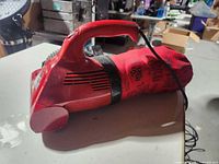 Left side view of Dirt Devil Ultra handheld vacuum showing overall shape, dust bag and cord