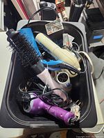 Top view of bin showing Conair blow dryer, blue brush dryer, purple dryer, pink curling iron, hair rollers