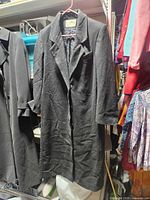 Front view of black wool trench coat hanging