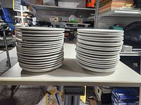 Two stacks of white plates on table