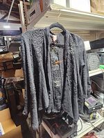 Front view of black knit lace-trim cardigan on hanger
