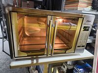 Front view showing Oster digital French door toaster oven powered on
