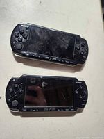 Front view of two Sony PSP-2001 consoles showing screens and controls
