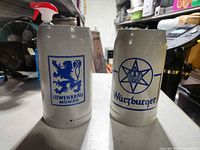Front view of both stoneware beer steins displaying Löwenbräu and Würzburger logos