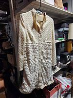 Full view of long cream lace jacket hanging