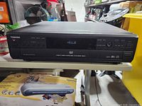 Front view showing Toshiba logo, display lit, disc tray and controls