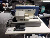 Overall view of White sewing machine on its metal base with foot pedal