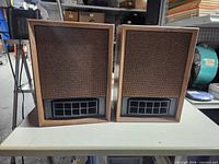 Front view of both speakers showing grille cloth and plastic port