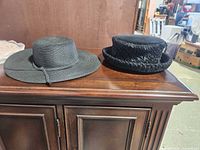 Two black hats: braided straw wide-brim and wool textured short-brim
